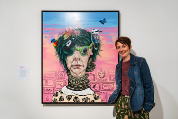 Person standing next to a colorful framed artwork on a white wall