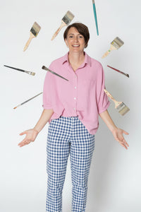 Person wearing a pink shirt with paintbrushes around them on a white background